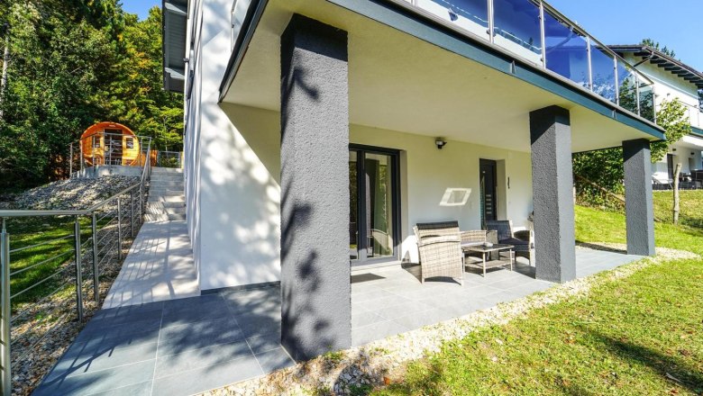 Ferienhaus Waxeneck, © Michaela Narath Terrasse eines modernen Ferienhauses mit Gartenmöbeln und angrenzendem Garten.