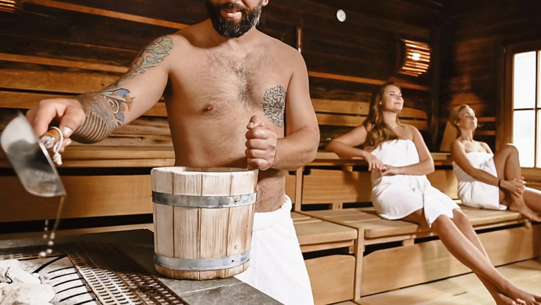 Würflacher Wellnesswelt, © A. Drazdansky @ TheVerve - Agentur Mann gießt Wasser in Sauna, zwei Frauen sitzen entspannt.