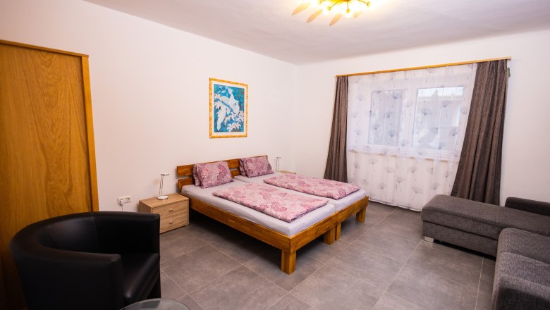 Ferienwohnung zum Nachbarn, © Peter Prandstetter, Julian Eisenkirchner Schlafzimmer mit Doppelbett, Sofa und Sessel.