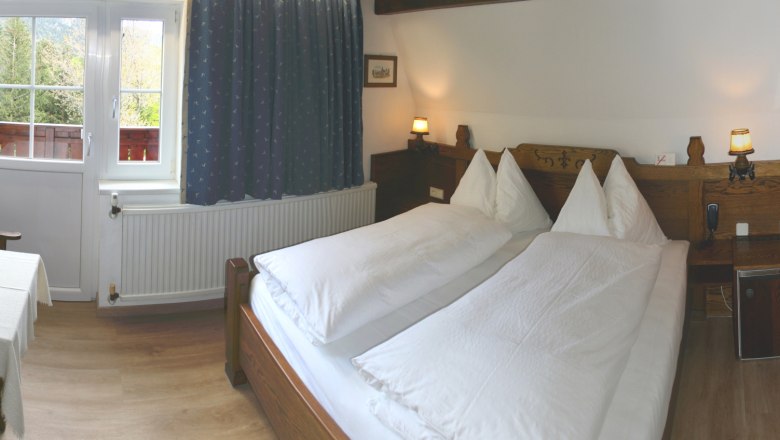 Apartment 1, © Marianne Gschaider Gemütliches Schlafzimmer mit Doppelbett, Holzmöbeln und Fenster mit Blick ins Grüne.