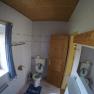 WC Ferienwohnung 1, © dmgrauszer Badezimmer mit Toilette, Holzdecke und Fenster mit blauem Vorhang.