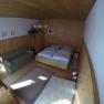 Schlafzimmer Ferienwohnung 1, © dmgrauszer Ein gemütliches Schlafzimmer mit Holzwänden, einem Doppelbett, einem Sofa und einem Teppich auf Holzboden.