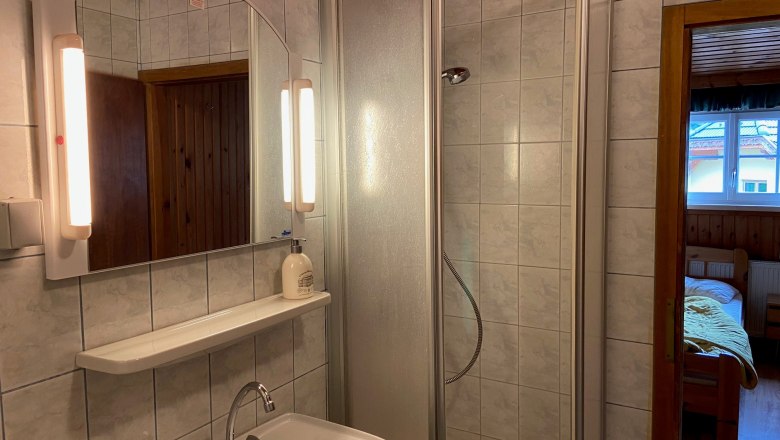 Badezimmer, © Wiener Alpen Badezimmer mit Dusche, Waschbecken und Spiegel mit Beleuchtung.