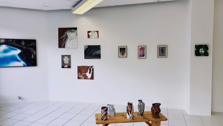 kunstraum-konrad, © Stefan Schuster Galerieraum mit Kunstwerken an der Wand und Keramiken auf einem Holztisch.