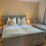 Schlafzimmer, © Marianne Gschaider Gemütliches Schlafzimmer mit Doppelbett und Einzelbett, zwei Nachttischlampen und Vorhängen.