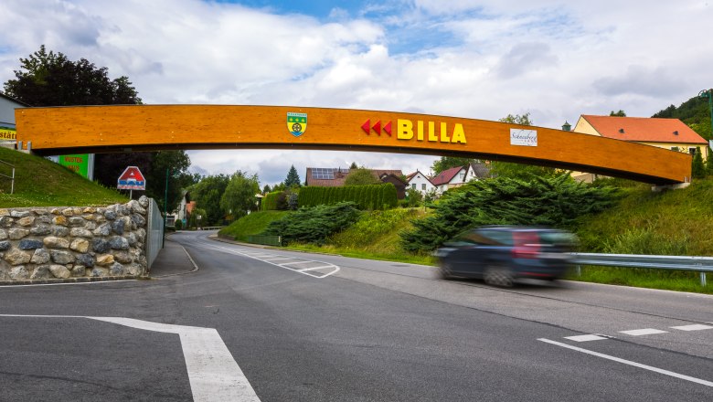 Billa-Brücke Willendorf/Höflein, © Wiener Alpen/Christian Kremsl Eine Holzbrücke mit dem Schriftzug 'BILLA' überspannt eine Straße in einer ländlichen Umgebung.