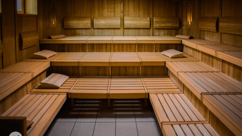 Bio Farblichtsauna, © TheVerve-Agentur (theverve.at) Innenansicht einer leeren Holzsauna mit mehreren Sitzreihen und Kopfstützen.