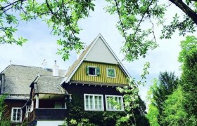 Hausansicht, © Berger Ein traditionelles Haus mit Satteldach, umgeben von grünen Bäumen und Pflanzen.