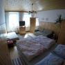 Schlafzimmer Ferienwohnung 1, © dmgrauszer Gemütliches Schlafzimmer mit Doppelbett, Sofa, TV und Holzmöbeln in einer Ferienwohnung.