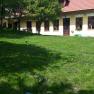 Garten vor den Ferienwohnungen, © dmgrauszer Grüner Garten vor einem gelben Gebäude mit roten Dachziegeln und mehreren Fenstern.