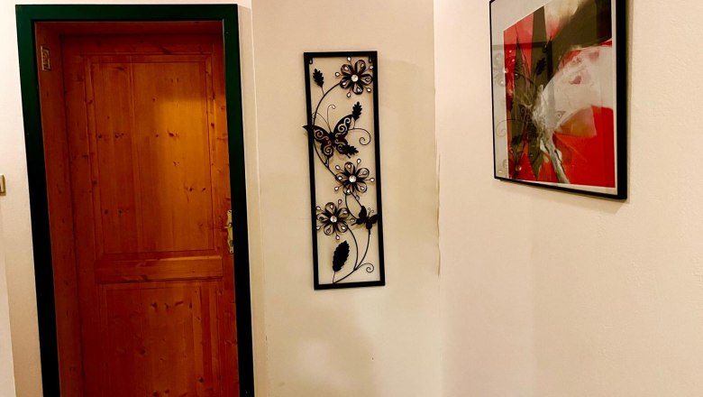 Frühstückspension Csenar, © Christine Kreiderits Flur mit Holztür, Wanddekoration und abstraktem Bild.
