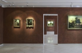 Ausstellungsräume im Gauermann Museum, © Wiener Alpen, Foto: Bene Croy Innenansicht eines Museums mit Gemälden an braunen Wänden.