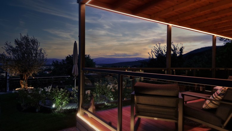 Abendstimmung auf einer Terrasse mit Blick auf die Berge und einen Garten.