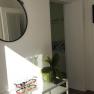 Innenansicht einer Ferienwohnung mit Spiegel, Pflanze und Wanddekoration.