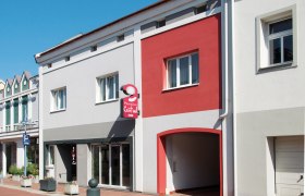 Fassade der Pension Central mit grauen und roten Wänden, einem Schild und Fenstern.