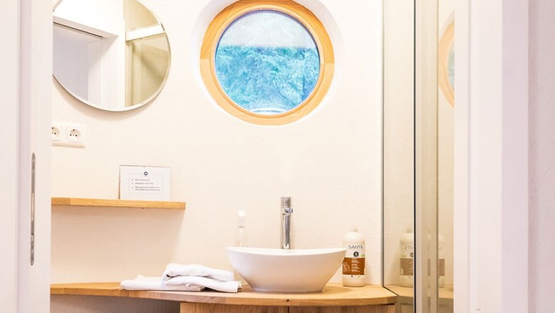 Modernes Badezimmer mit rundem Fenster und Waschbecken.