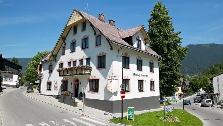 Ein traditioneller Gasthof an einer Straßenecke in einer ländlichen Umgebung.