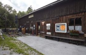 Holzgebäude mit Schildern und Blumen, Teil einer Ausstellung.