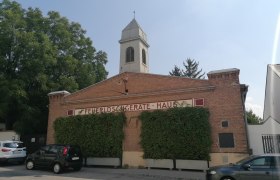 Altes Feuerwehrhaus in Bad Fischau mit Backsteinfassade und Turm.
