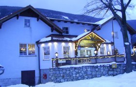 Ein Gasthof im Winter mit Schnee bedeckt, beleuchtet und dekoriert.