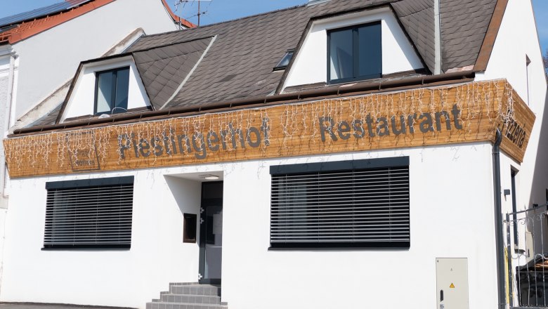 Fassade eines Restaurants mit dem Namen Piestingerhof, dekoriert mit Lichterketten.