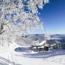 Winterlandschaft mit Sesselliftstation, verschneiten B&auml;umen und Bergen im Hintergrund.