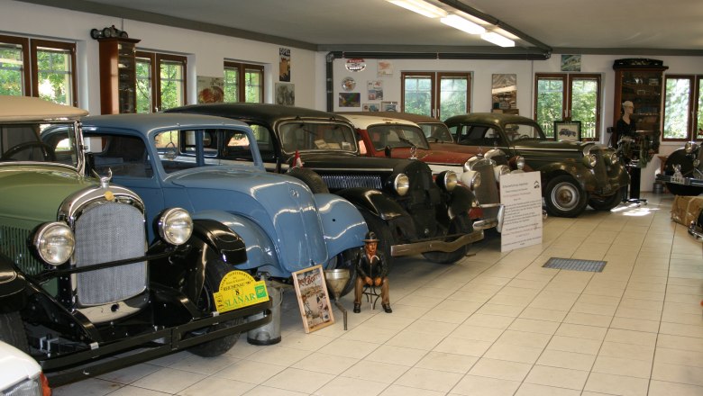 Innenansicht eines Oldtimermuseums mit mehreren klassischen Autos in einer Reihe.