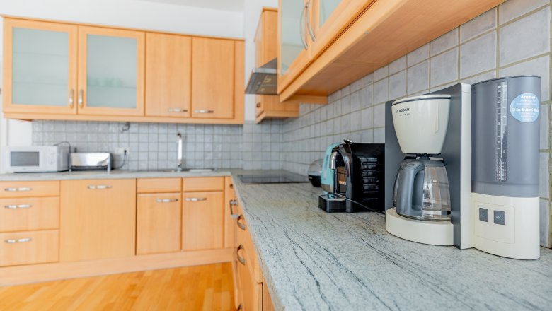Moderne K&uuml;che mit Holzschr&auml;nken, Kaffeemaschine und Toaster auf der Arbeitsplatte.