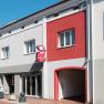 Fassade der Pension Central mit grauen und roten Wänden, einem Schild und Fenstern.