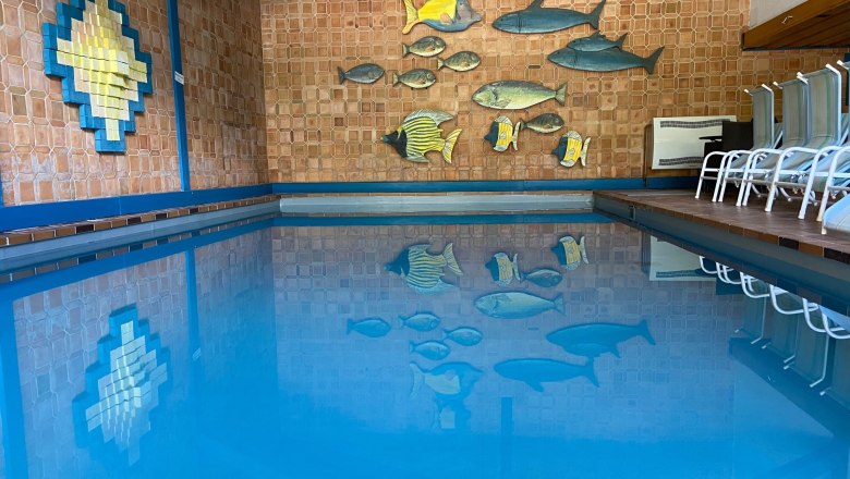 Innenpool mit blauer Wasseroberfläche und Wanddekoration aus Fischen.