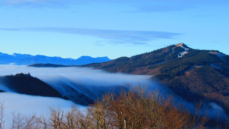 Blick von einem Berg auf nebelverhangene Täler und bewaldete Hügel.