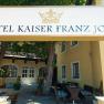 Eingang des Hotel Kaiser Franz Josef mit Schild und Bäumen.