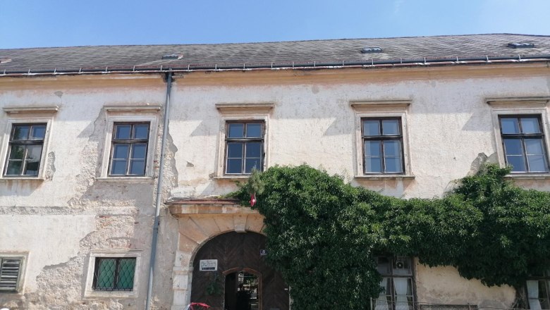 Altes Gebäude mit Efeu bewachsen und einem klassischen weißen Auto davor.