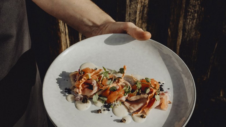 Ein Teller mit kunstvoll angerichtetem Vitello Tonnato, garniert mit Kr&auml;utern.