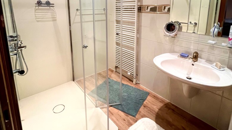 Modernes Badezimmer mit Dusche, Waschbecken und Handtuchheizung.