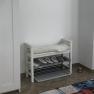 Vorraum einer Ferienwohnung mit Schuhregal, Bank und Pflanze.
