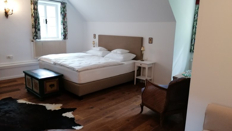 Gemütliches Schlafzimmer mit Doppelbett, Holzboden, Teppich und antiken Möbeln.