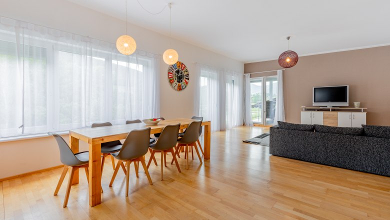 Moderner Essbereich mit Holztisch, grauen St&uuml;hlen und gro&szlig;er Fensterfront.