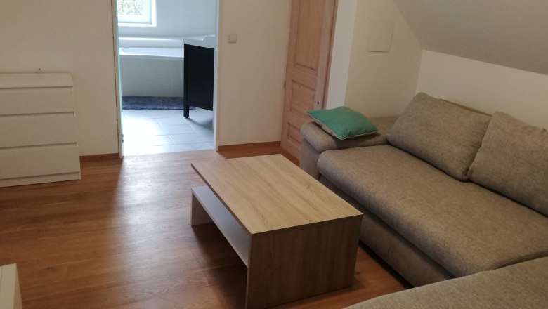 Wohnzimmer mit Ecksofa, Couchtisch und Blick ins Badezimmer.