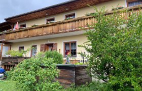 Zweistöckiges Haus mit Holzbalkon und Garten.
