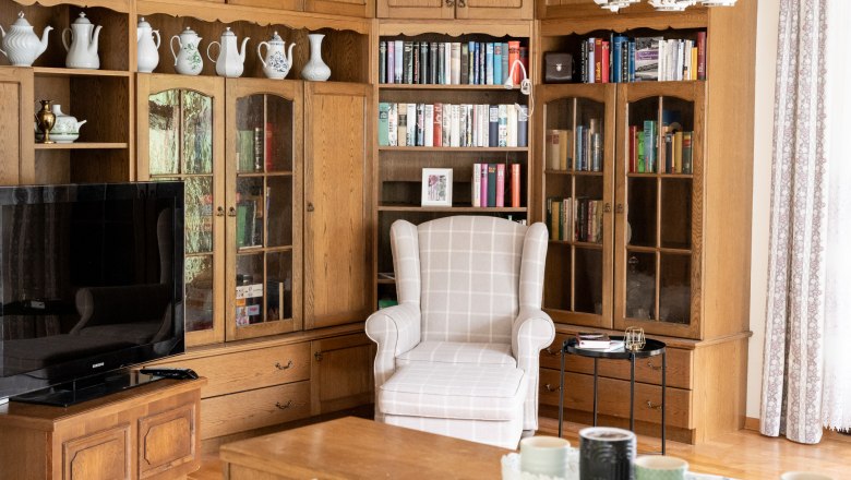 Wohnzimmer mit B&uuml;cherregal, Sessel und Fernseher.