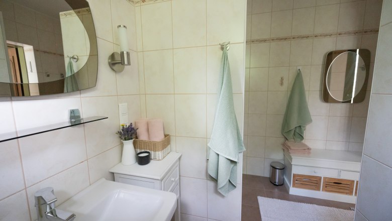 Modernes Badezimmer mit Waschbecken, Spiegel, Handt&uuml;chern und Dekoration.