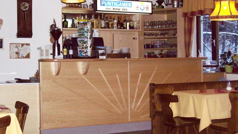 Innenansicht eines Gasthauses mit Theke und Tischen.
