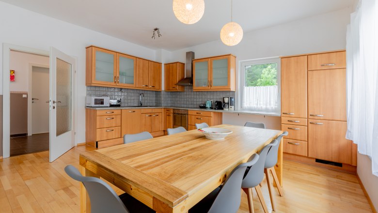 Moderne K&uuml;che mit Holzm&ouml;beln und gro&szlig;em Esstisch.