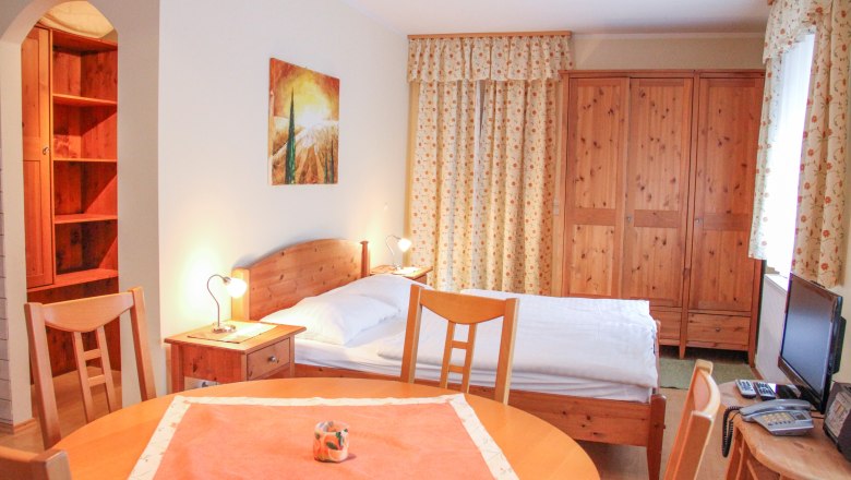 Kleine Wohnung mit Holzm&ouml;beln, Bett, Tisch und Schrank.