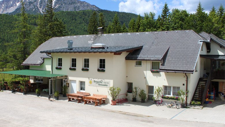 Berggasthof Mamauwiese vor bewaldeten Bergen.