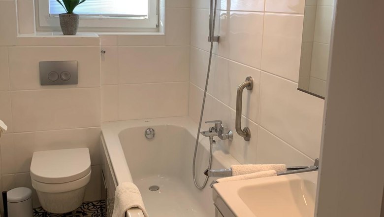 Modernes Badezimmer mit Badewanne, WC und Waschbecken.