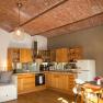 Gemütliche Küche mit Holzmöbeln, Ziegeldecke und Esstisch.