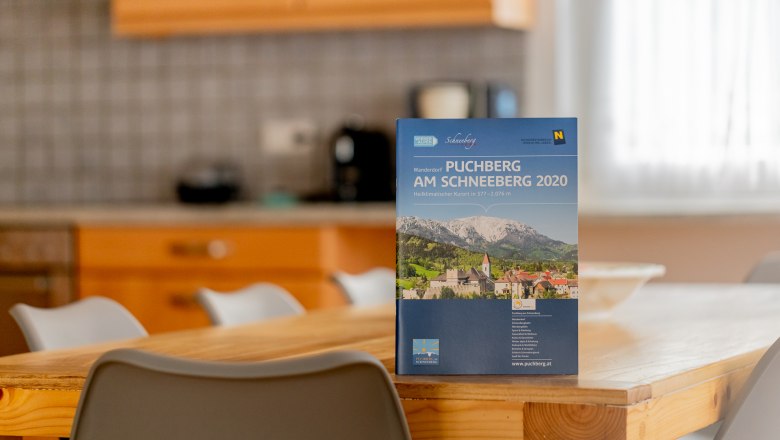 Ein Prospekt von Puchberg am Schneeberg steht auf einem Holztisch in einer K&uuml;che.