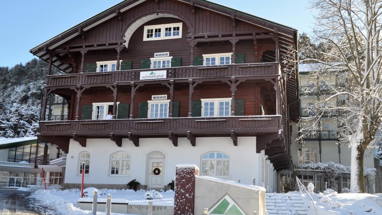 Ein traditionelles Gebäude namens Schneeberghof im Winter, umgeben von Schnee und Bäumen.